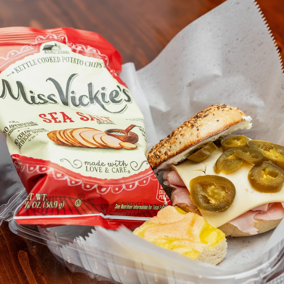 Deli sandwich with cheese and jalapeños beside a bag of Miss Vickie's sea salt kettle-cooked potato chips.