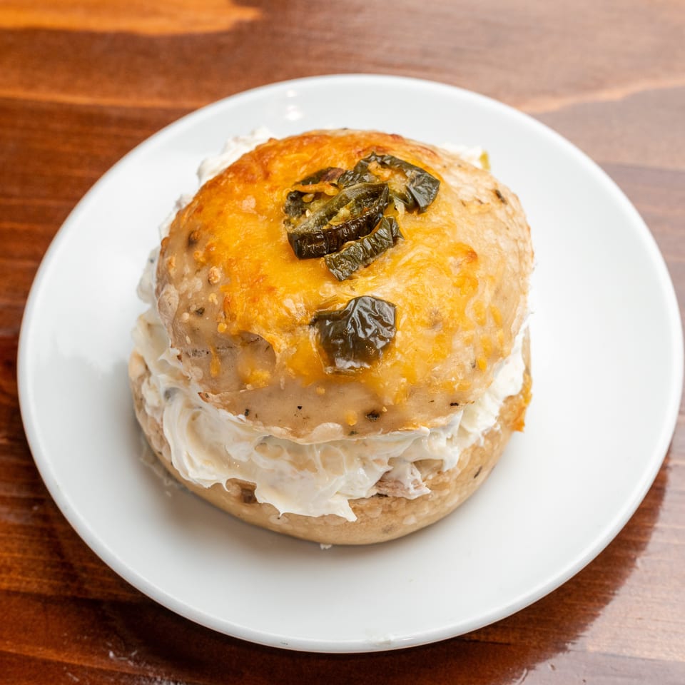Cheesy baked savory pastry topped with sliced green peppers, served on a white plate over a wooden table.