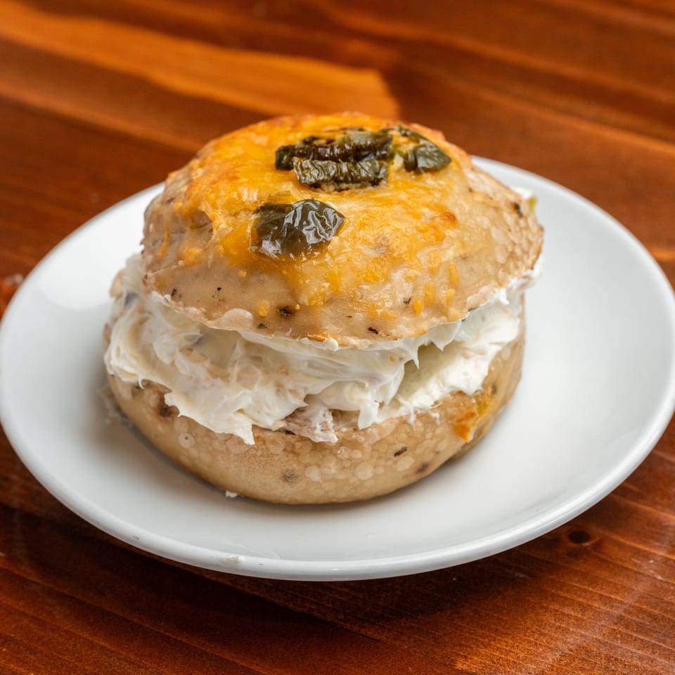 Golden baked pastry filled with creamy white filling, topped with melted cheese and dark olives, served on a white plate.